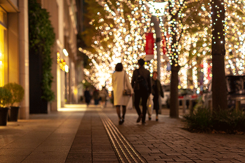 People walking down the street lit with Christmas lights